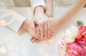 photo of women holding hands in marriage ceremony