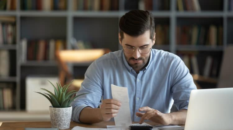 photo of man using a calculator and looking at a financial document