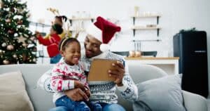 Stock photo of child sitting on father's lap in front of a Christmas tree