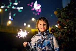 Preschool children, holding sparkler, celebrating new years eve outdoors, watching fireworks